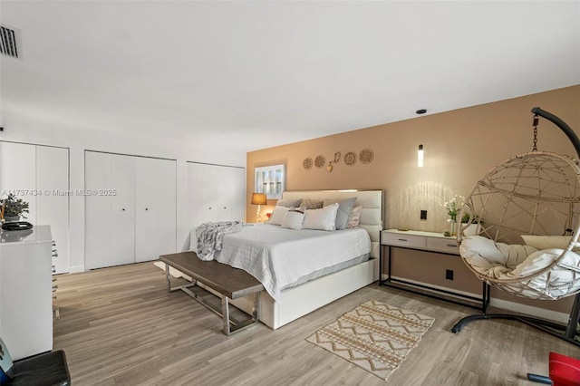 bedroom featuring two closets and light hardwood / wood-style floors