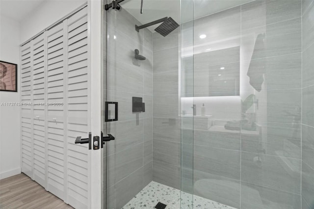 bathroom with wood-type flooring and a shower with shower door