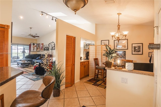 dining area featuring lofted ceiling, ceiling fan with notable chandelier, and light tile patterned floors