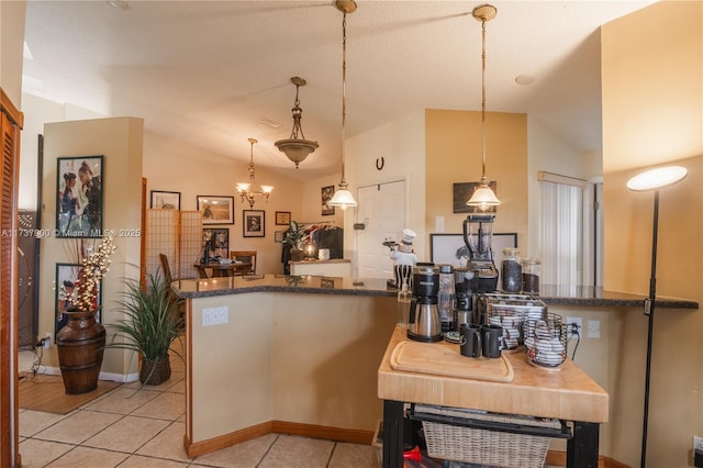 kitchen featuring hanging light fixtures, lofted ceiling, light tile patterned floors, and kitchen peninsula