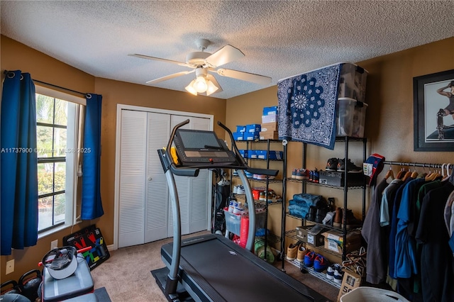 workout area featuring ceiling fan, carpet flooring, and a textured ceiling