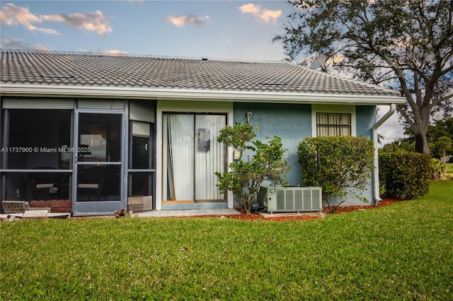 rear view of property with a yard and central air condition unit