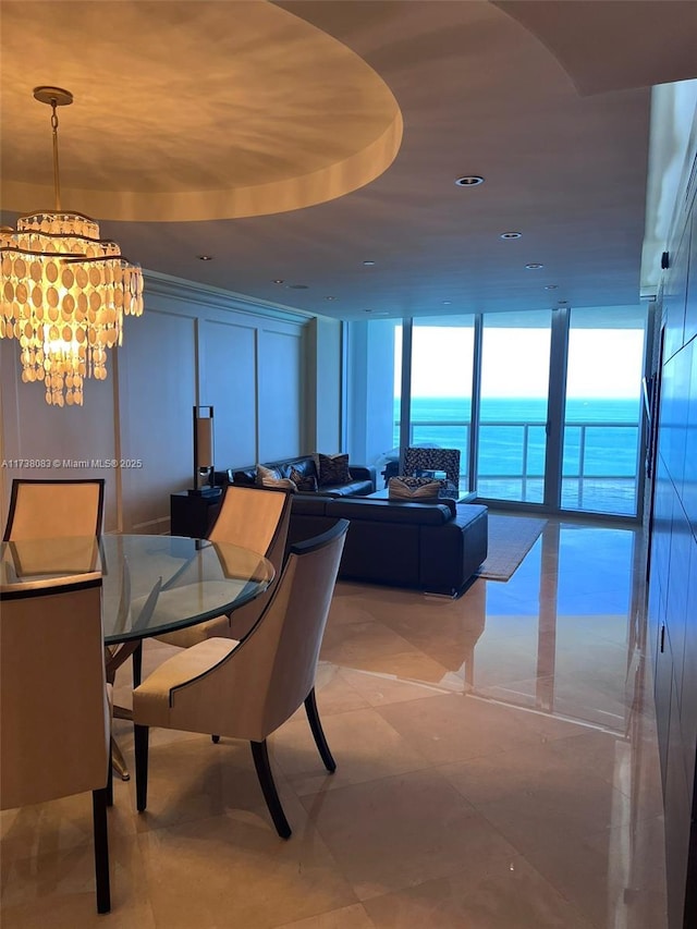 dining room featuring a water view, a wall of windows, and a notable chandelier