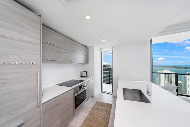 kitchen featuring sink, oven, floor to ceiling windows, a water view, and black electric cooktop