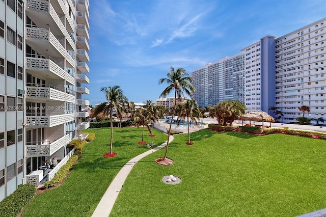 surrounding community featuring a pool, a view of city, and a lawn