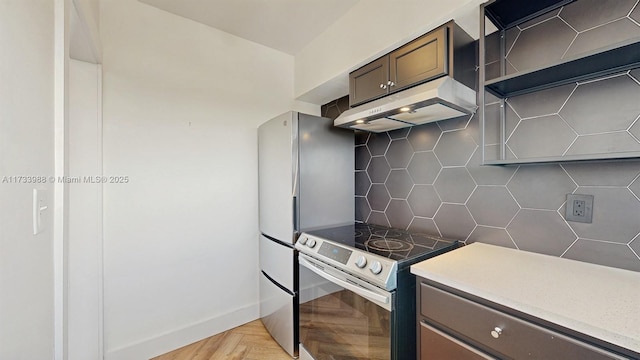 kitchen with dark brown cabinetry, electric range, baseboards, under cabinet range hood, and backsplash