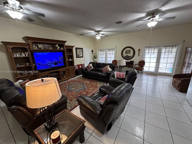 living room featuring ceiling fan, light tile patterned floors, a textured ceiling, and french doors