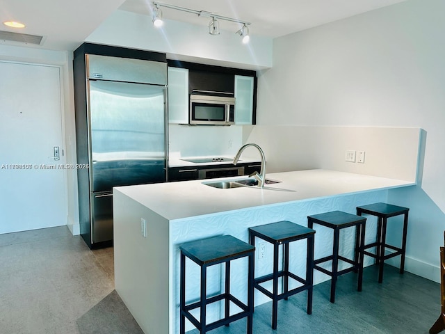 kitchen featuring sink, a breakfast bar, kitchen peninsula, and appliances with stainless steel finishes