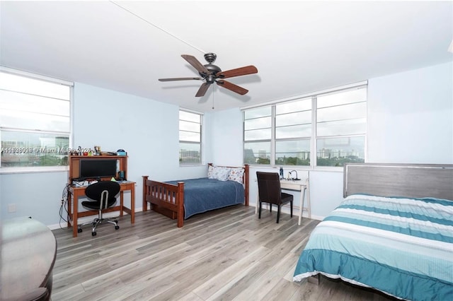 bedroom featuring ceiling fan, multiple windows, and light wood-type flooring