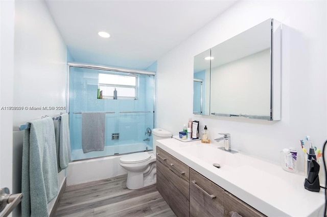 full bathroom featuring bath / shower combo with glass door, wood-type flooring, vanity, and toilet