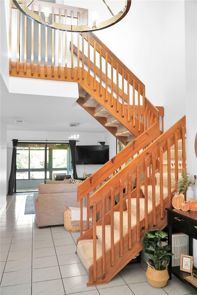 stairs featuring a towering ceiling and tile patterned flooring