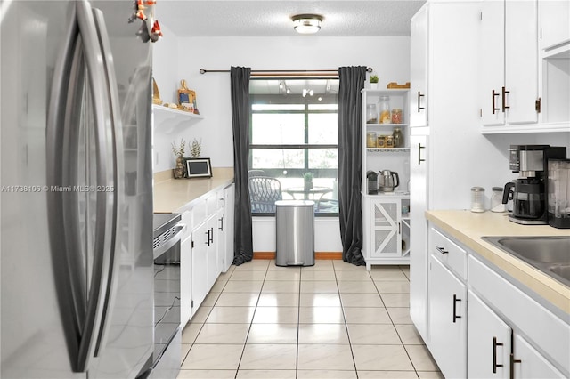 kitchen with sink, white cabinetry, a textured ceiling, light tile patterned floors, and appliances with stainless steel finishes