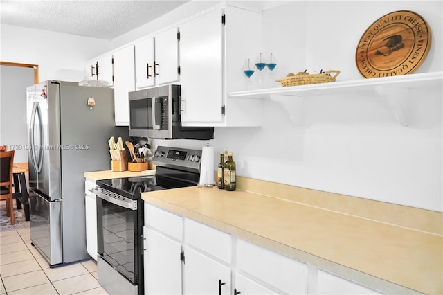 kitchen with white cabinetry, appliances with stainless steel finishes, light tile patterned flooring, and a textured ceiling