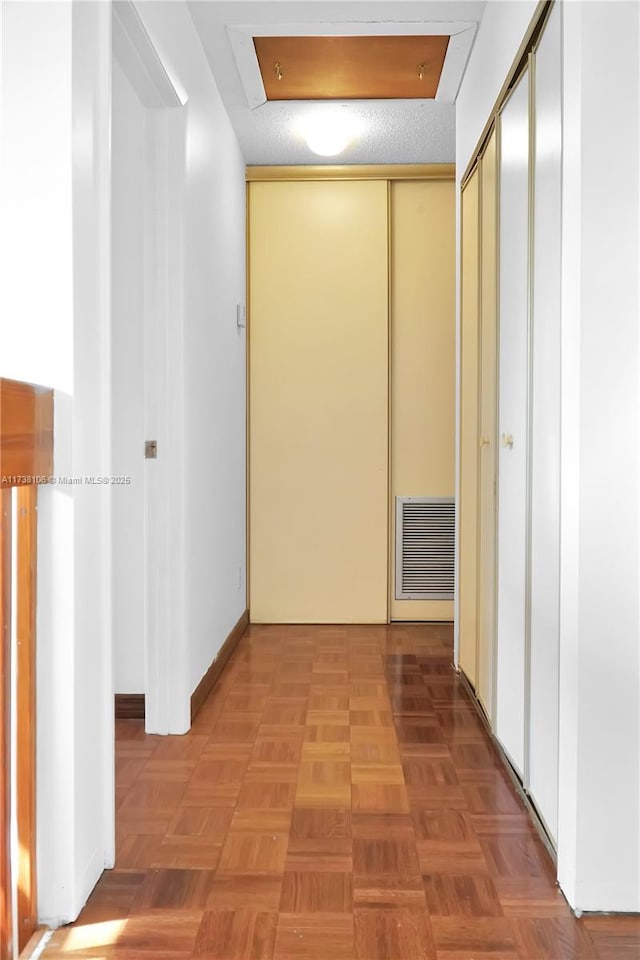 hallway featuring parquet flooring and a textured ceiling