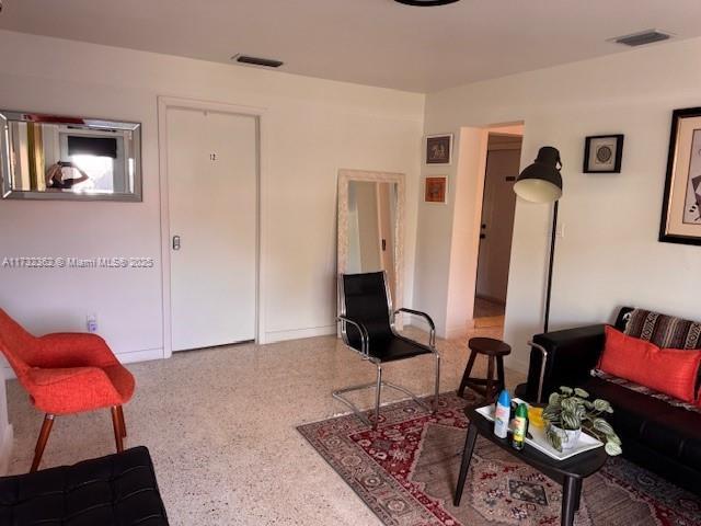 living area featuring visible vents and speckled floor
