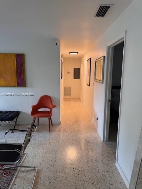 hall featuring visible vents, speckled floor, and a sink