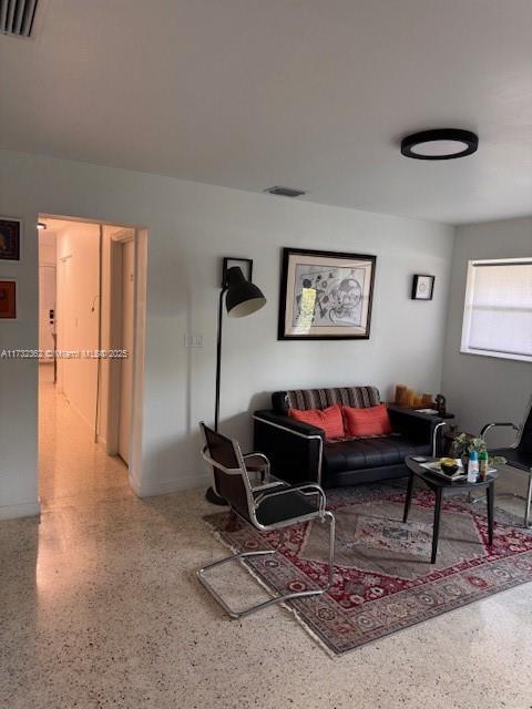 living room featuring visible vents and speckled floor