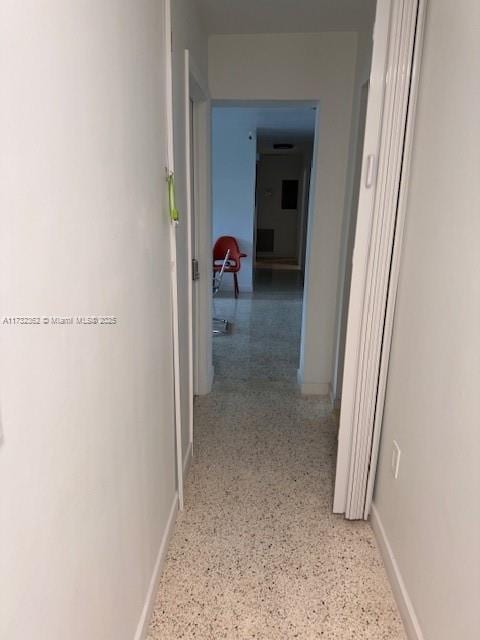 hall with speckled floor and baseboards