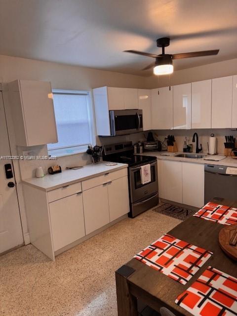 kitchen with a sink, white cabinets, stainless steel appliances, and light countertops