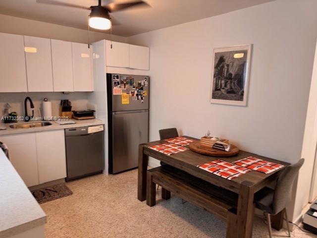 kitchen featuring a sink, a ceiling fan, light countertops, dishwasher, and freestanding refrigerator
