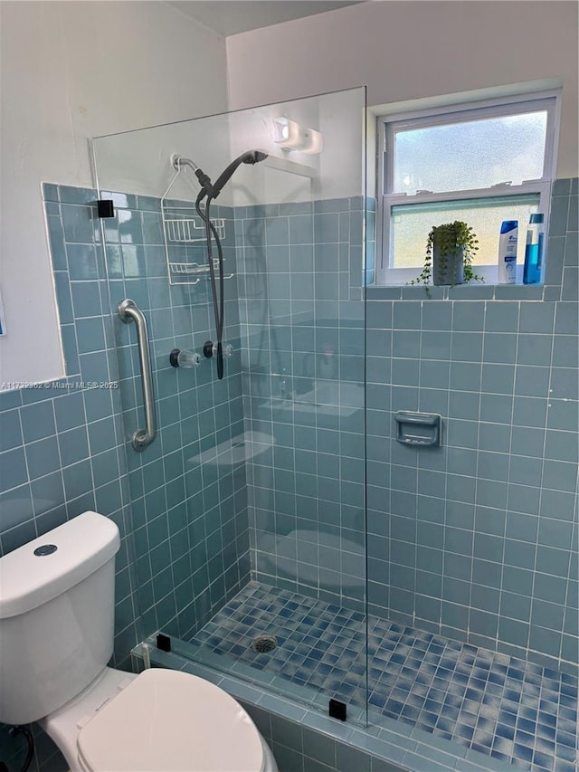 full bathroom with a tile shower and toilet