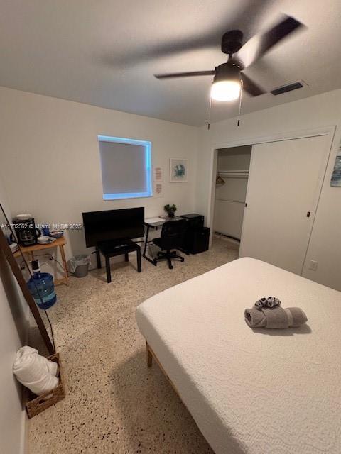 bedroom featuring speckled floor, a closet, visible vents, and ceiling fan