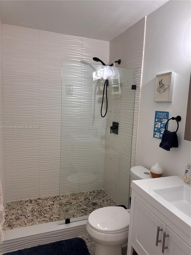 bathroom with tiled shower, toilet, and vanity