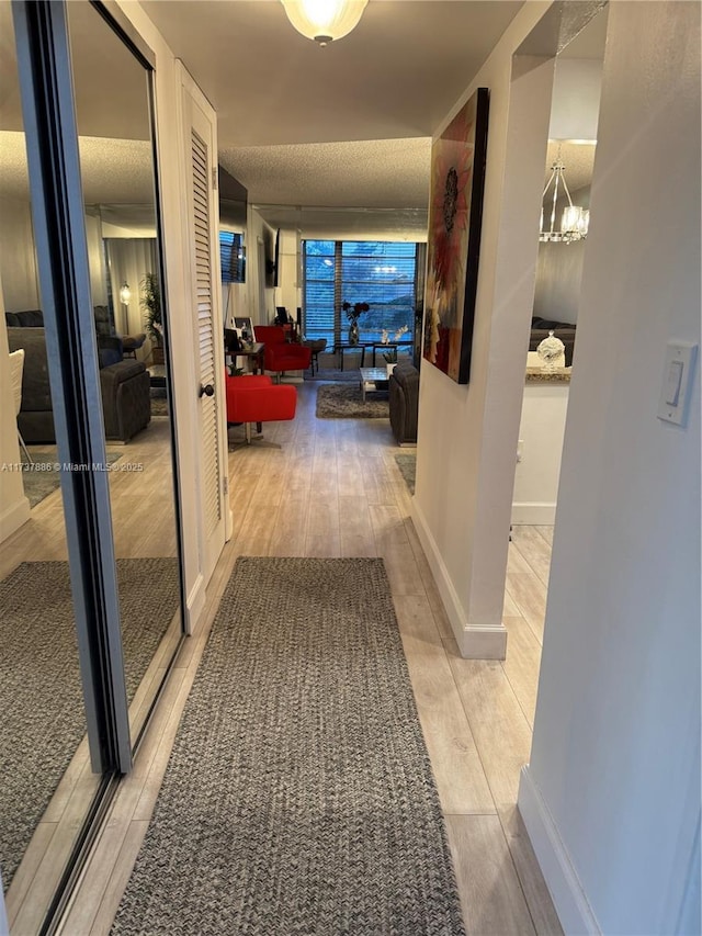 hallway featuring a chandelier and light wood-type flooring