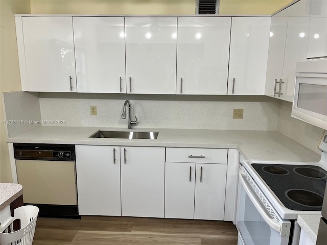 kitchen with dark wood-type flooring, sink, tasteful backsplash, white appliances, and white cabinets