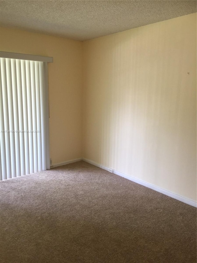 unfurnished room featuring carpet floors, a textured ceiling, and baseboards