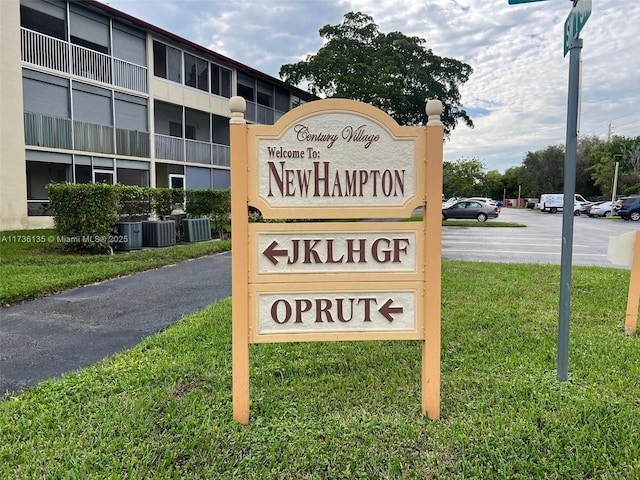 community sign with uncovered parking and a lawn