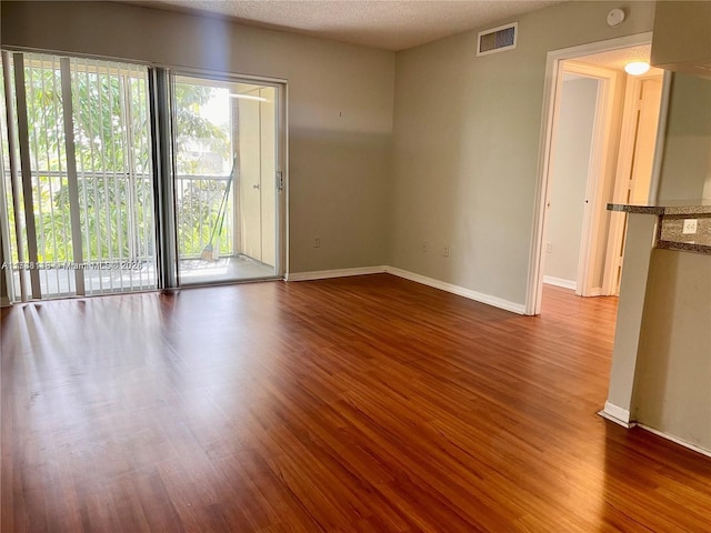 spare room with wood-type flooring, plenty of natural light, and a textured ceiling