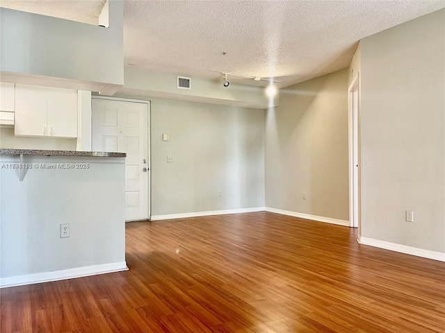 interior space featuring hardwood / wood-style flooring, rail lighting, and a textured ceiling