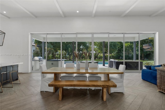 dining space featuring beam ceiling, a wealth of natural light, and light parquet floors