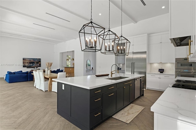 kitchen featuring decorative light fixtures, white cabinetry, sink, a large island with sink, and light parquet flooring