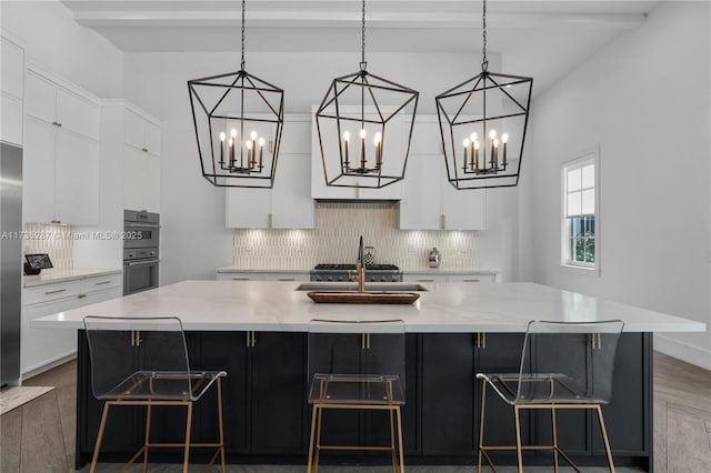 kitchen featuring hanging light fixtures, a large island, sink, and white cabinets