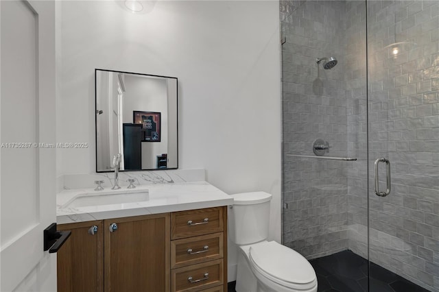 bathroom featuring vanity, a shower with shower door, and toilet