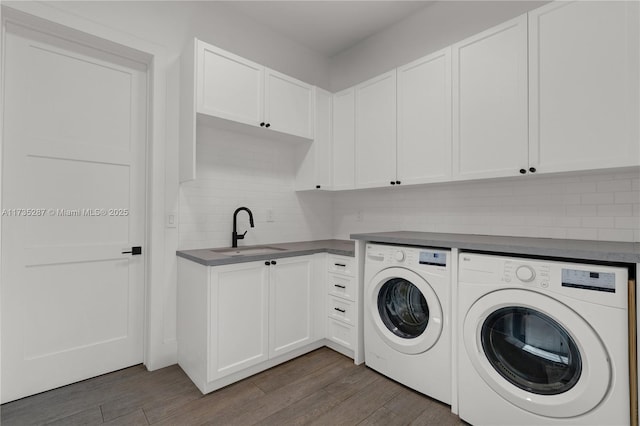 clothes washing area featuring cabinets, sink, dark wood-type flooring, and washing machine and clothes dryer