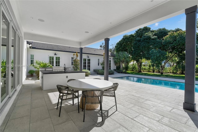 view of swimming pool featuring a patio area, a wet bar, and exterior kitchen