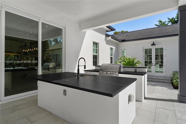 kitchen featuring french doors, sink, and a center island with sink