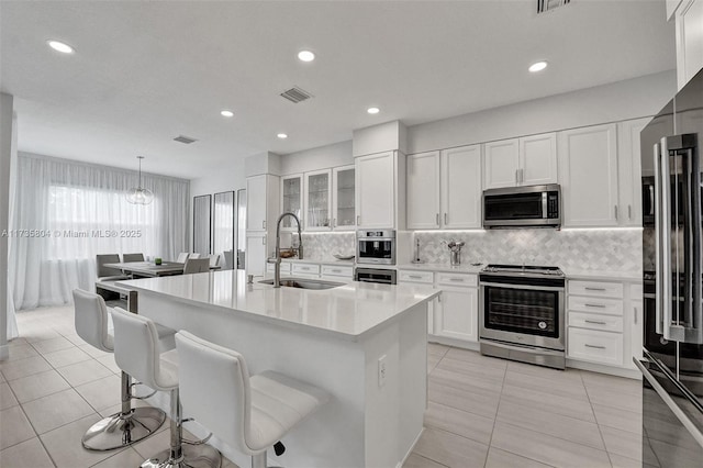 kitchen featuring sink, a breakfast bar area, white cabinetry, an island with sink, and stainless steel appliances