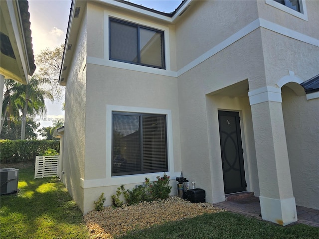 doorway to property with cooling unit and a lawn