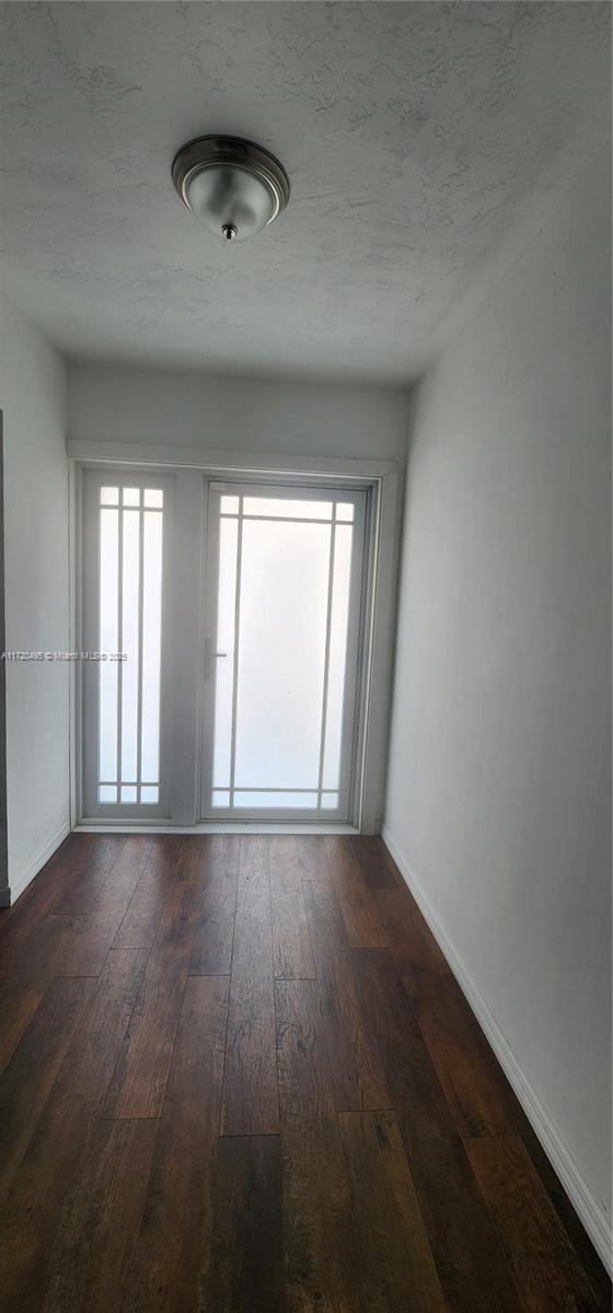 empty room featuring a healthy amount of sunlight, dark hardwood / wood-style floors, and a textured ceiling