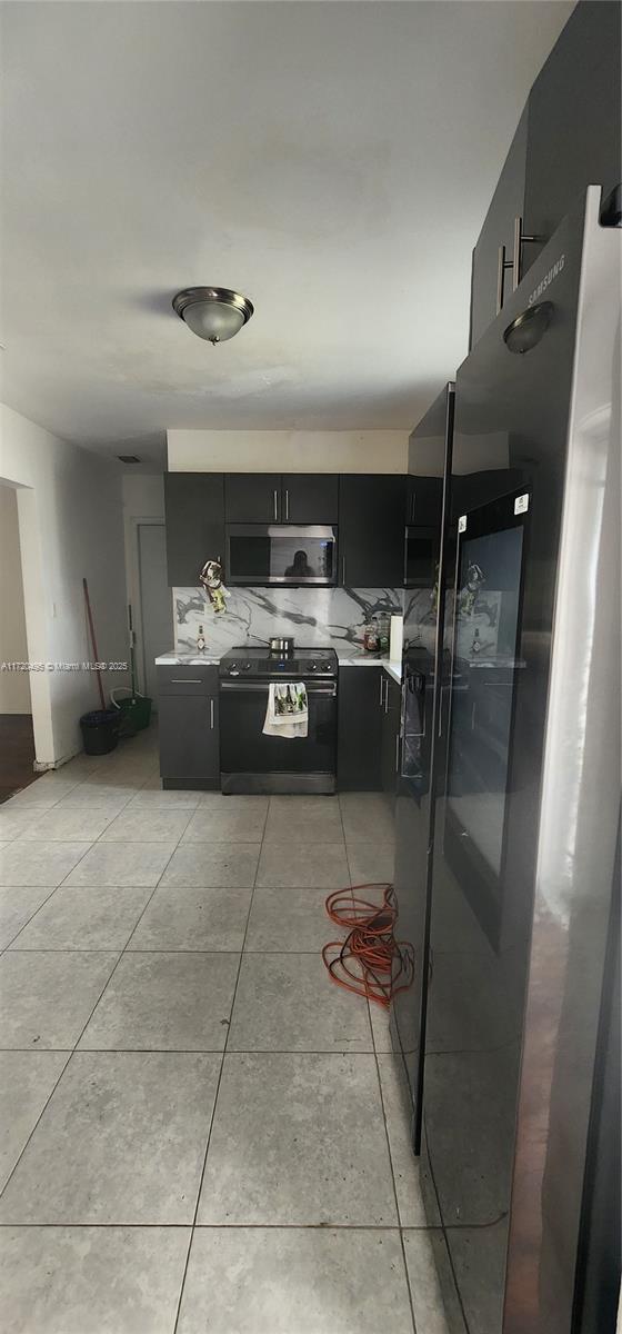 kitchen with refrigerator, light tile patterned floors, decorative backsplash, and electric range