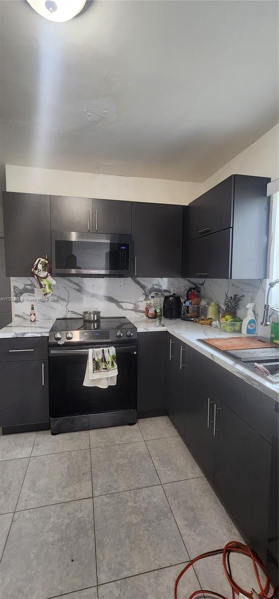 kitchen featuring tasteful backsplash, sink, light tile patterned floors, and black electric range