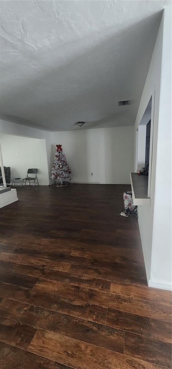 bonus room with dark wood-type flooring and a textured ceiling