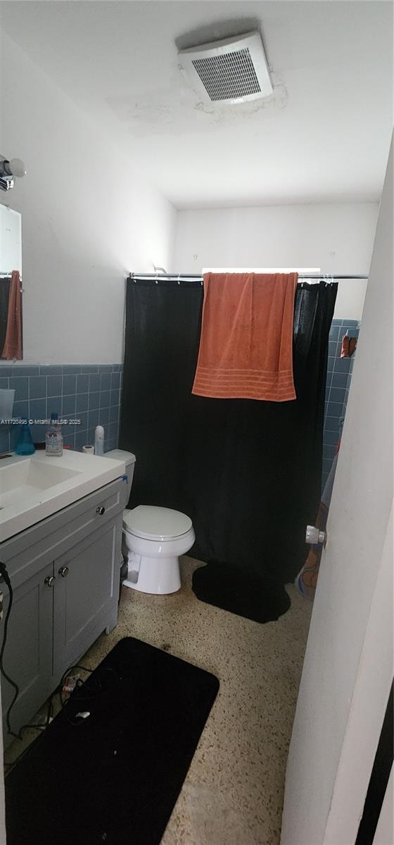 bathroom featuring vanity, tile walls, curtained shower, and toilet