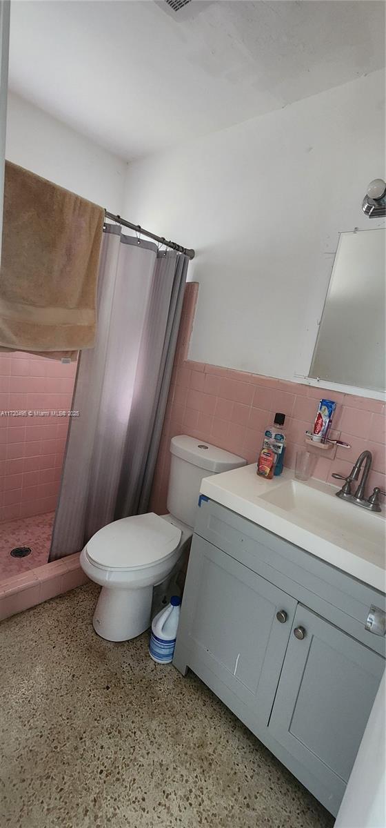 bathroom with vanity, toilet, tile walls, and a shower with shower curtain