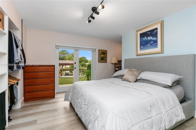 bedroom with access to outside, track lighting, and light hardwood / wood-style floors