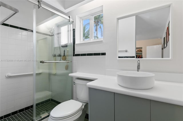 bathroom featuring vanity, a shower with shower door, tile walls, and toilet